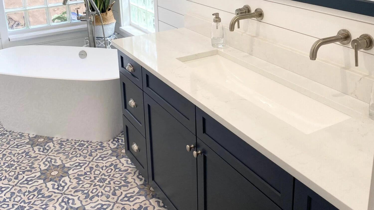 A bathroom with a coastal theme, including a blue vanity and patterned tile