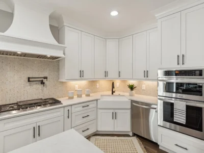 Kitchen cabinets with sink in corner and craftsman style range hood